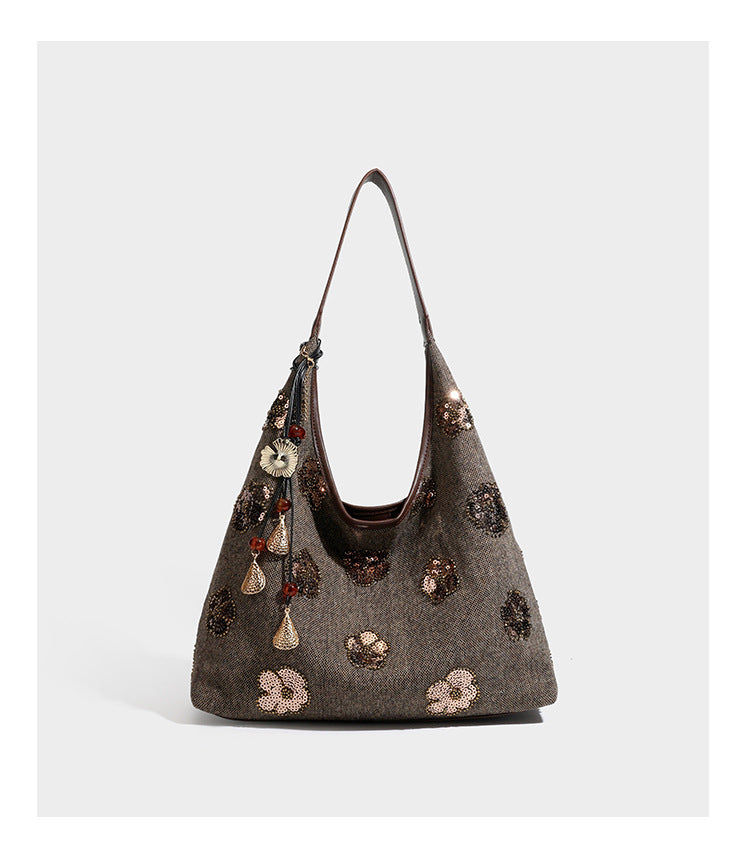 Lässig fallende, trapezförmige Schulter-Tote in Anthrazitgrau mit floralen Paillettenmotiven in Silber, Riemen in Lederoptik und herabhängendem Perlenbesatz