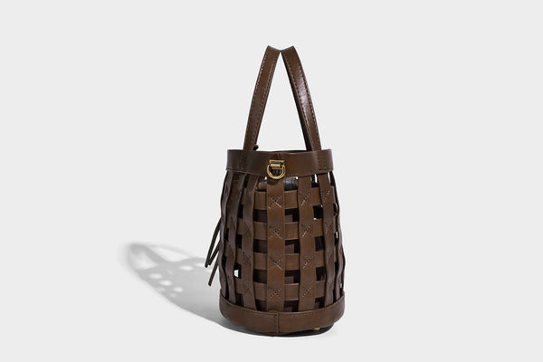 Small woven lattice bucket bag in brown leather-look finish with beaded tassel charm, dual top handles, and detachable