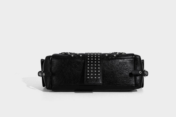 Schwarze, glänzende Henkeltasche mit genarbter Struktur, silberfarbenen Nieten, Riemendetail mit Schnalle, zwei Henkeln und breitem, mit Nieten besetztem Schulterriemen