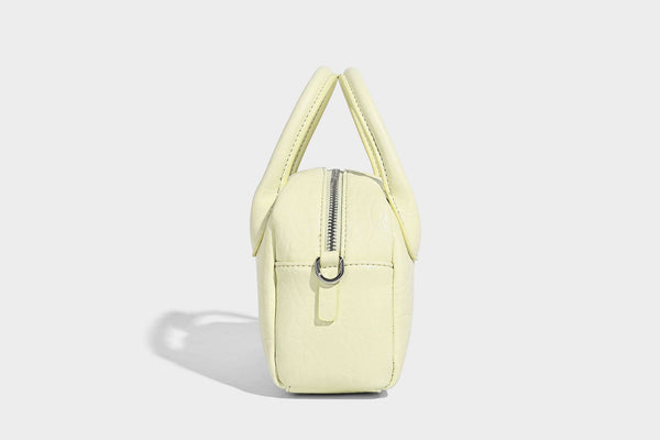 Mini-Tasche mit strukturierter Kuppelform und Tragegriff, in Pastellgelb mit genarbter Lederoptik, silberfarbenen Metallbeschlägen und abnehmbarem
