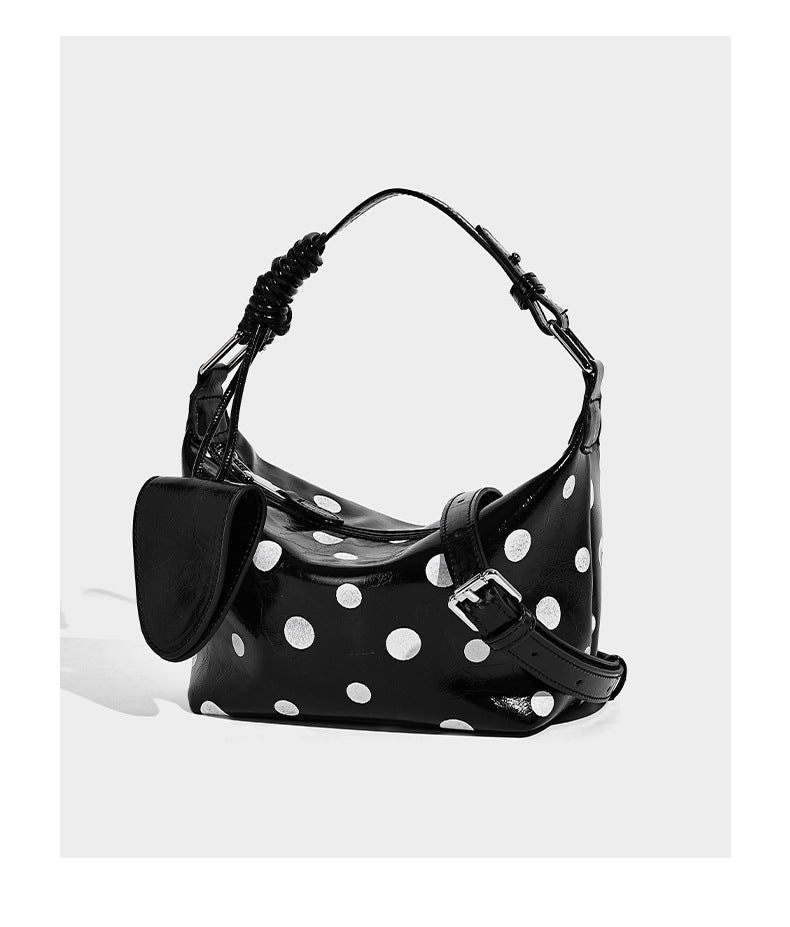 Schultertasche in glänzender Lederoptik mit Tupfenmuster, aufgesetzter Mini-Tasche vorne, Reißverschluss oben und verstellbarem Riemen, Detailansicht