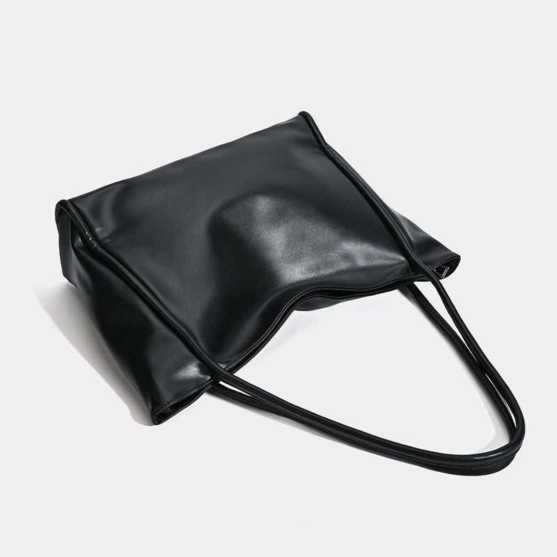 Große schwarze Tote-Bag in glänzender Lederoptik mit zwei Schulterriemen und sanft geschwungener Oberkante, Detailansicht 4