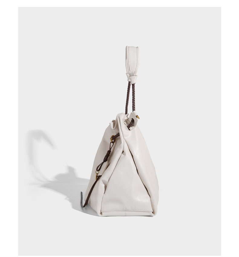 Cream slouchy drawstring bucket bag with braided cord, beaded tassel charm, and gold-tone ring hardware, detail view 9