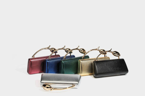Structured rectangular metallic woven clutch bag with sculptural gold-tone leaf top handle and detachable chain strap, detail