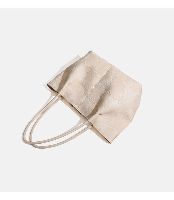 Large open-top tote bag with raised diamond-lattice stitching, long double shoulder handles, and gold-tone magnetic snap