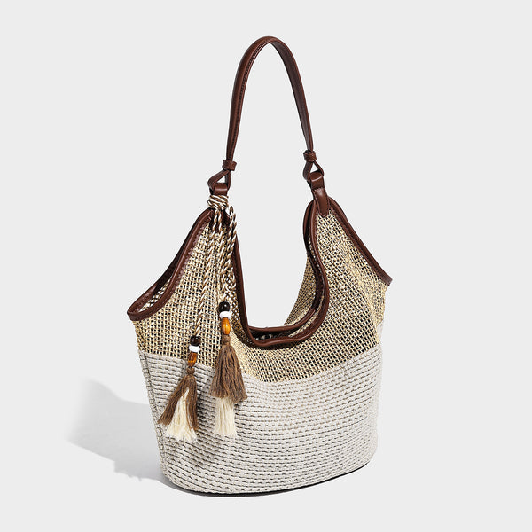 Two-tone beige and cream woven straw hobo shoulder bag with brown leather-look trim, long shoulder strap, and tassel-bead