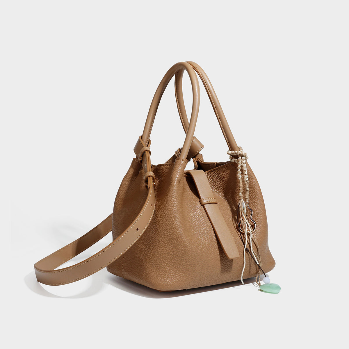 Pebbled leather-look bucket tote bag with rolled double handles, drawstring closure, braided cord charm, and detachable