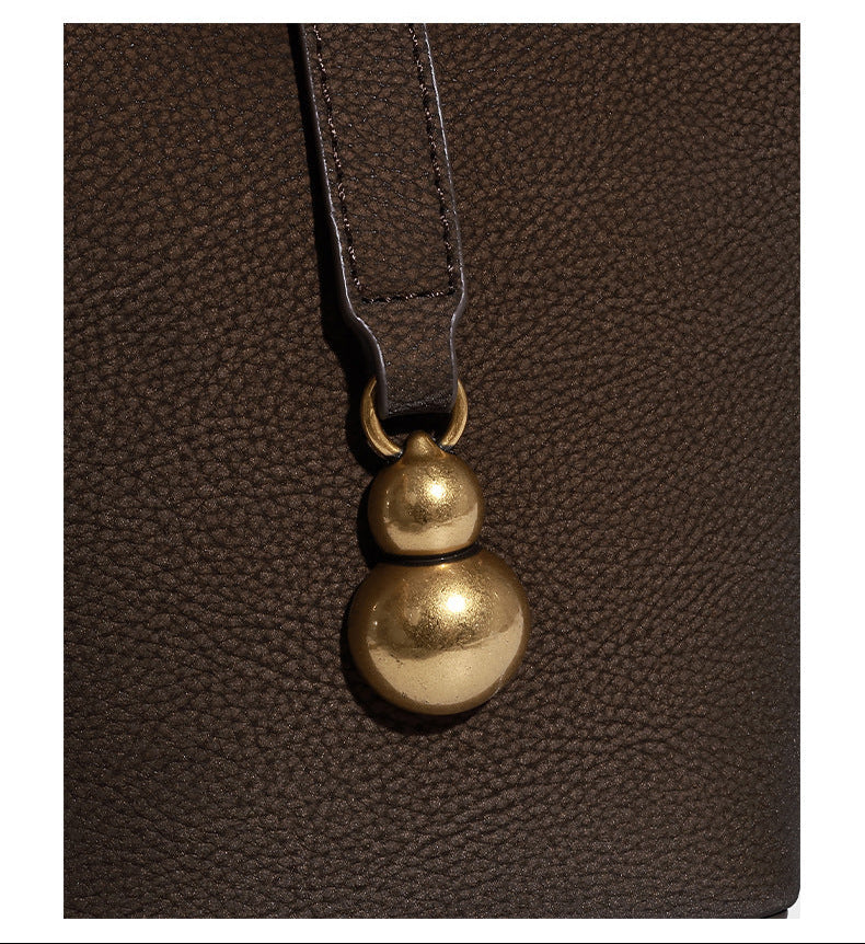 Kleine matte Beuteltasche mit genarbter Oberfläche, antikgoldfarbenen Ringbeschlägen, Perlen- und Quastenanhänger, kurzen Tragegriffen oben und