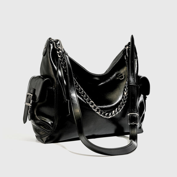 Slouchy hobo shoulder bag with glossy leather-look finish, silver-tone chain drape across front, side buckle pockets, and