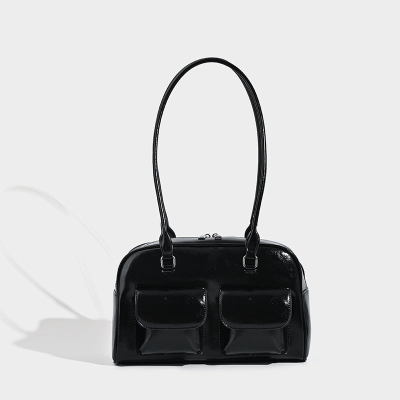 Structured glossy leather-look bowling bag with two front flap pockets, zip-top closure, and long twin shoulder straps, front