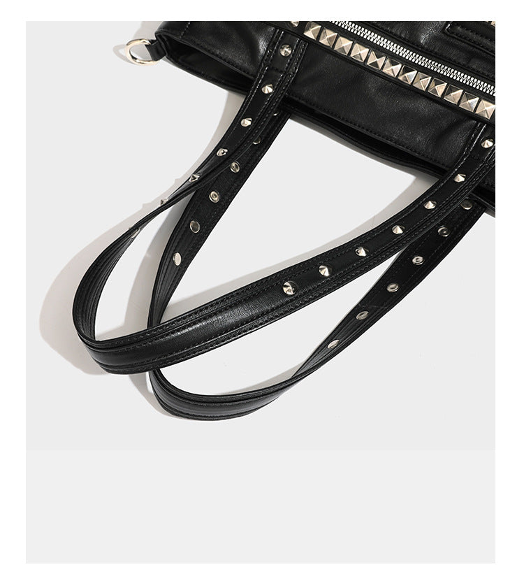 Black leather-look tote bag with silver pyramid studs on handles and front panel, multiple flap and zip exterior pockets