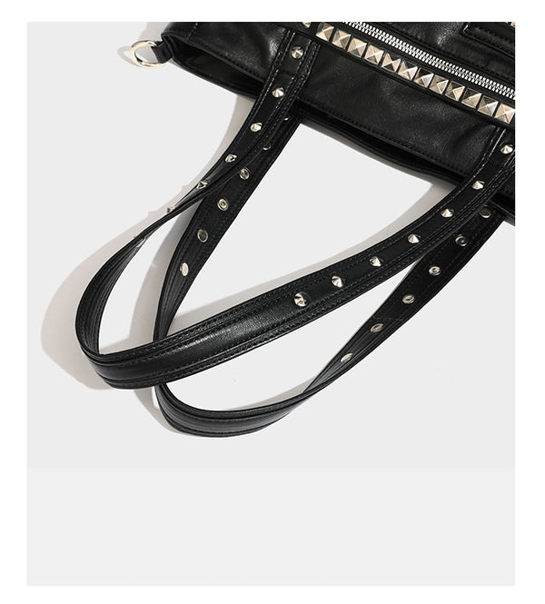 Black leather-look tote bag with silver pyramid studs on handles and front panel, multiple flap and zip exterior pockets
