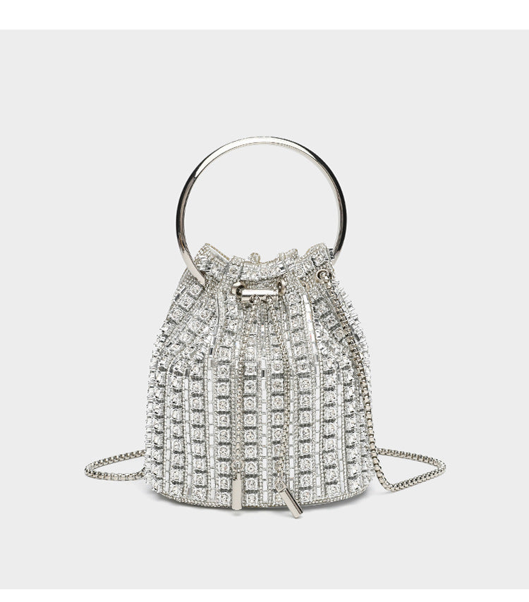 Mini crystal rhinestone bucket bag with circular ring top handle, drawstring closure, and silver chain shoulder strap, detail