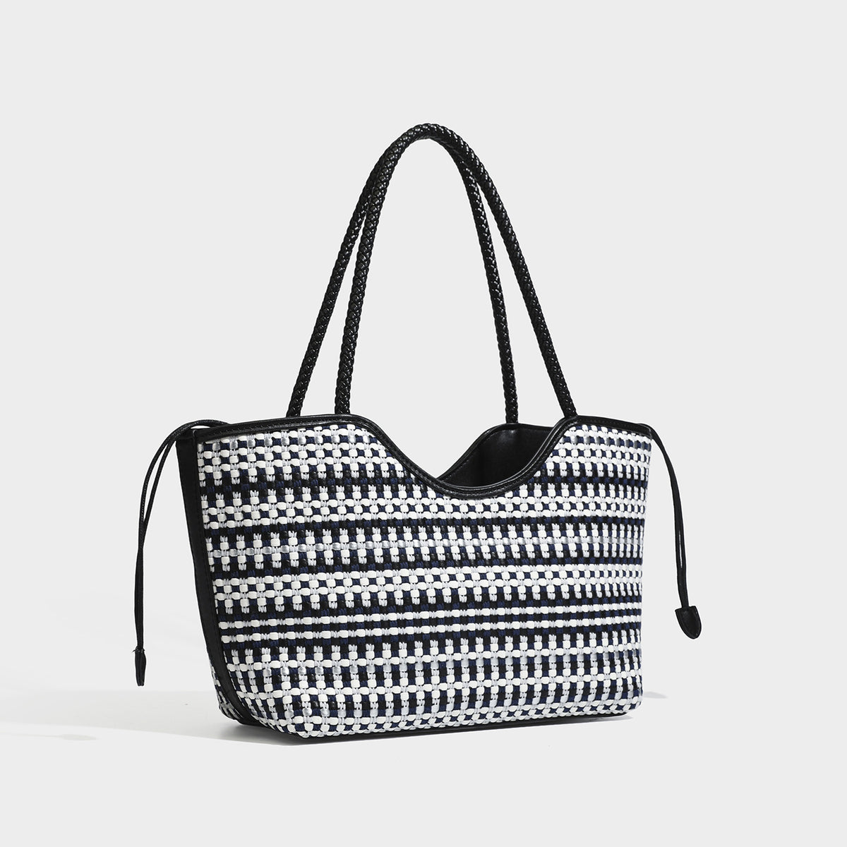 Large woven checker-pattern tote bag with dark braided shoulder straps, leather-look trim, and drawstring side ties, detail