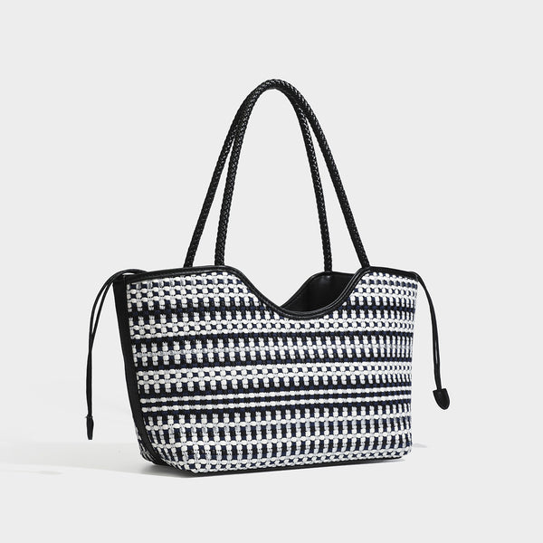 Large woven checker-pattern tote bag with dark braided shoulder straps, leather-look trim, and drawstring side ties, detail