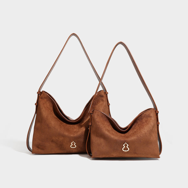 Slouchy suede-finish brown shoulder bag with long single strap and small gold-tone logo emblem on front, detail view 44