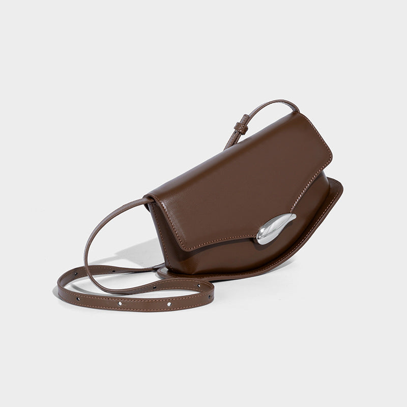 Small structured saddle bag with glossy leather-look finish, angular flap front, silver-tone metal clasp, and slim