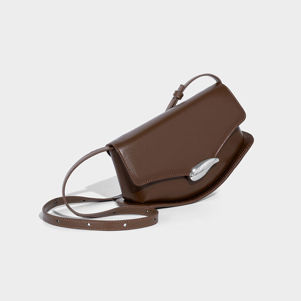 Small structured saddle bag with glossy leather-look finish, angular flap front, silver-tone metal clasp, and slim