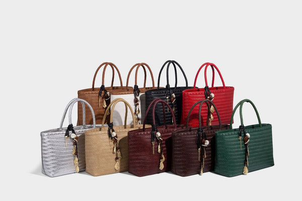 Structured woven-texture tote bag with brown braided top handles, decorative tassel charm, and detachable shoulder strap