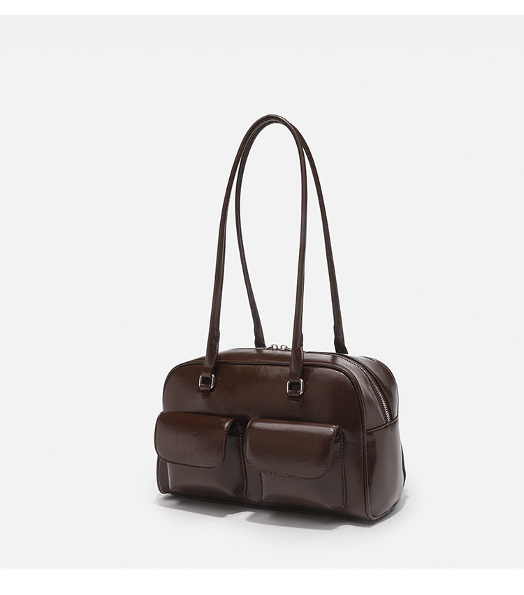 Structured glossy leather-look bowling shoulder bag with two front flap pockets, top zip closure, and long double shoulder