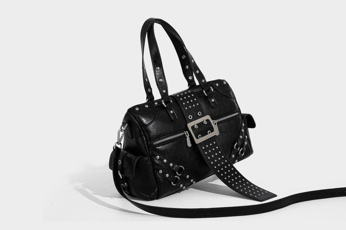 Schwarze, glänzende Henkeltasche mit genarbter Struktur, silberfarbenen Nieten, Riemendetail mit Schnalle, zwei Henkeln und breitem, mit Nieten besetztem Schulterriemen