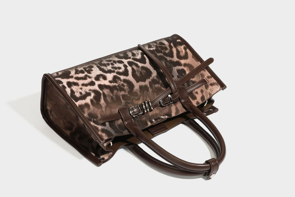 Structured leopard-print tote bag with glossy satin-like finish, dual rounded top handles, silver buckle-and-ring front
