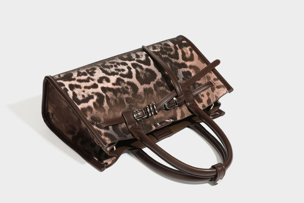 Structured leopard-print tote bag with glossy satin-like finish, dual rounded top handles, silver buckle-and-ring front