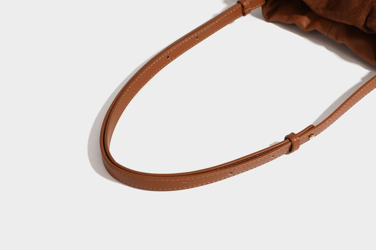 Suede-look drawstring shoulder bag in brown with smooth trim, knotted bead drawstring closure, slim adjustable strap, and