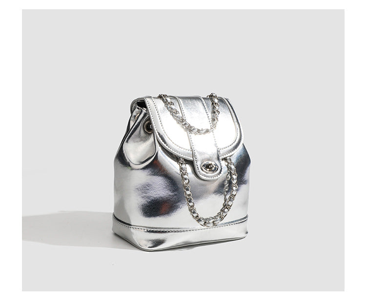 Kompakter Rucksack in Silbermetallic mit mehrfarbigen Kristallnieten, runder Klappe mit Drehverschluss und ineinander verflochtenem Silber