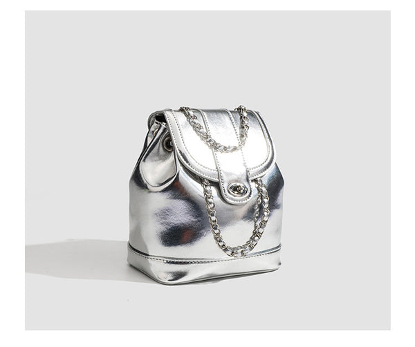 Kompakter Rucksack in Silbermetallic mit mehrfarbigen Kristallnieten, runder Klappe mit Drehverschluss und ineinander verflochtenem Silber