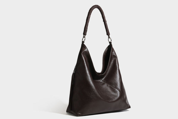Large slouchy hobo shoulder bag with braided top handle, smooth glossy leather-look finish, and silver-tone ring hardware