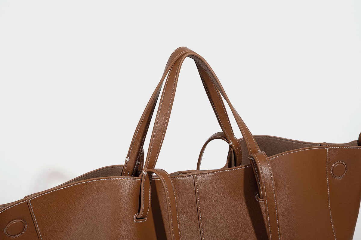 Große, formstabile trapezförmige Tote-Bag aus braunem Lederimitat mit genarbter Oberfläche, zwei Tragegriffen und seitlichen Bindebändern, Detail