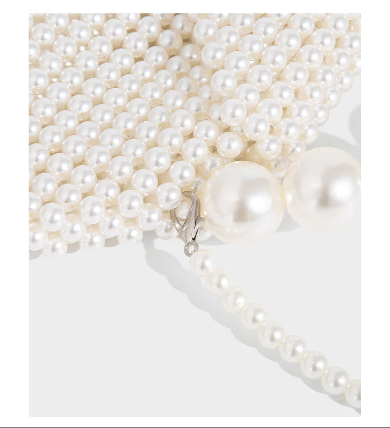 Small structured triangle clutch bag covered in glossy pearl beads with an arched pearl top handle and silver snap closure