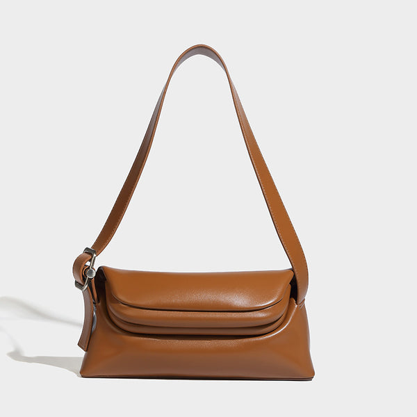 Compact structured baguette shoulder bag with smooth leather-look finish, zip top, and adjustable silver-buckle strap, detail