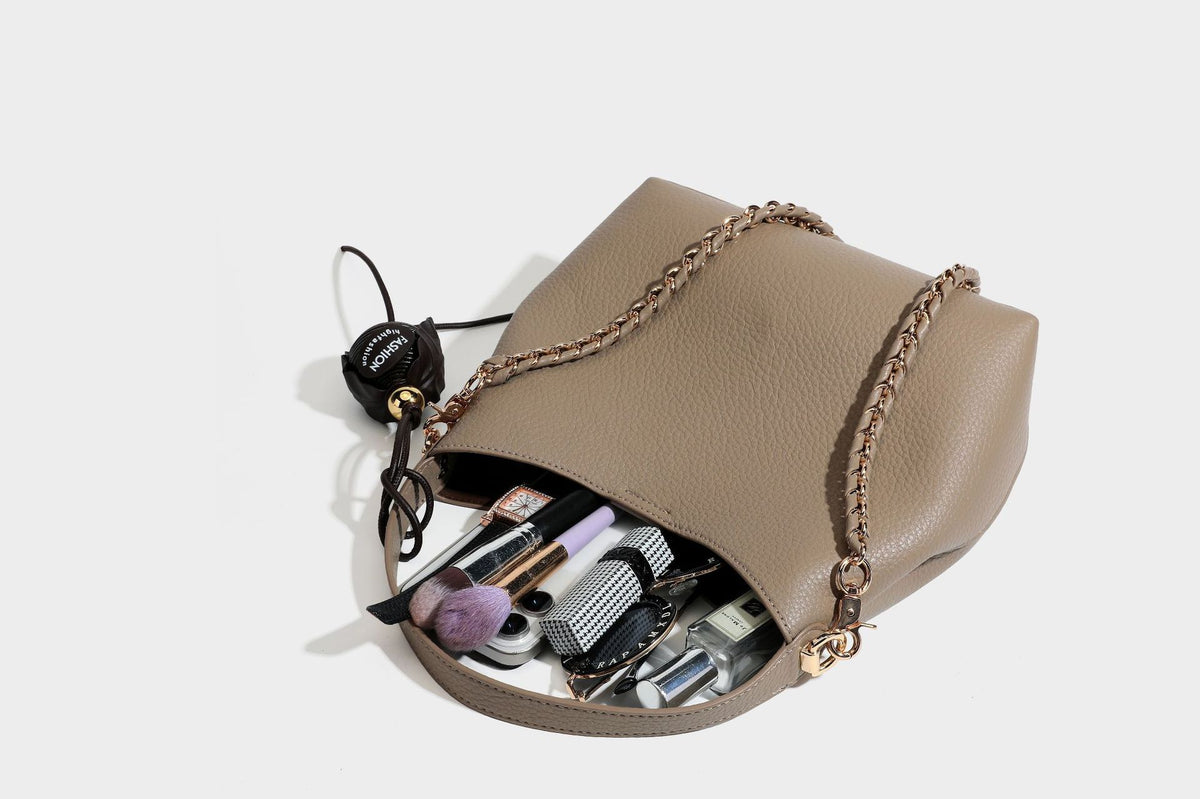 Schultertasche in genarbter Lederoptik im Hobo-Stil mit goldfarbener Kette, kurzem Tragegriff und dekorativem Anhänger an der Seite, Detailansicht