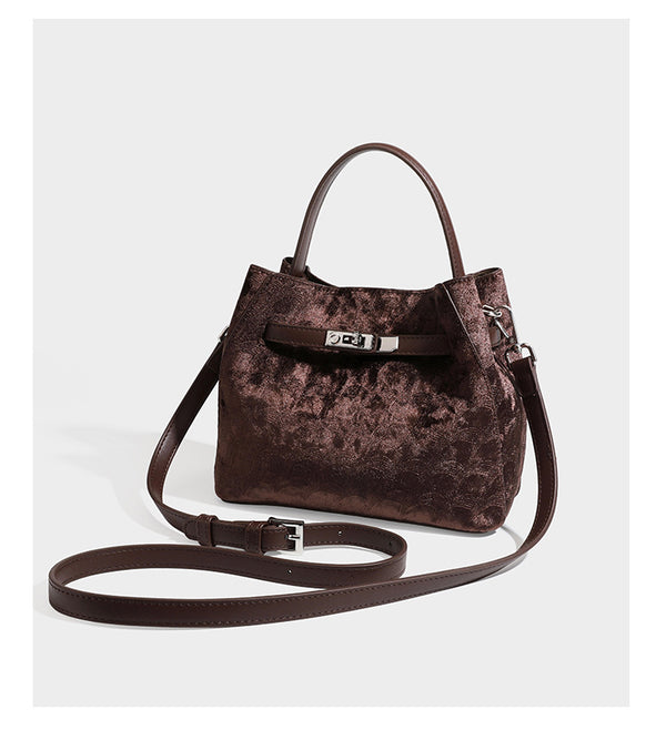 Small structured bucket satchel in embossed velvet-texture fabric with silver turn-lock hardware, rounded top handle, and