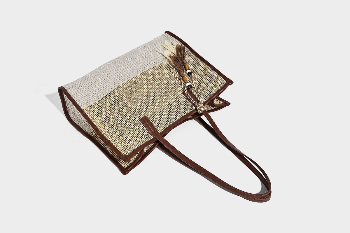 Große Tote-Bag aus grob geflochtenem Stroh in Beige und Creme mit dunkelbraunen Details in Lederoptik, langen Schulterriemen und einem mit Perlen verzierten