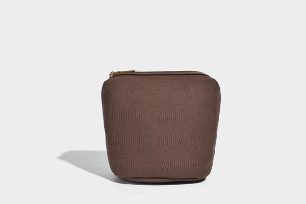 Small woven lattice bucket bag in brown leather-look finish with beaded tassel charm, dual top handles, and detachable