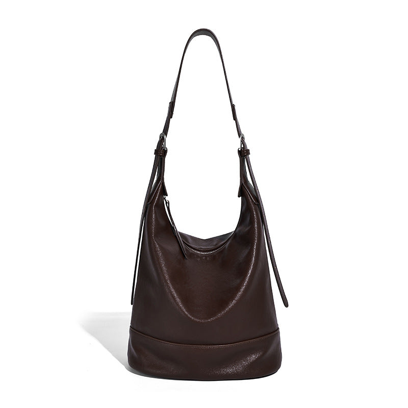 Slouchy bucket hobo shoulder bag in dark brown with glossy leather-look finish, top zip closure, and long adjustable, detail