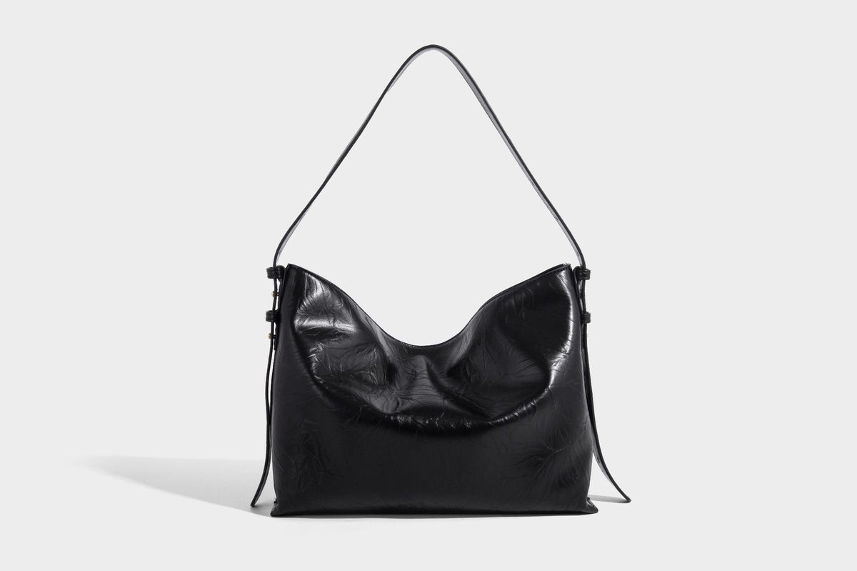 Large slouchy hobo shoulder bag in glossy crinkle leather-look finish with gold-tone emblem hardware and adjustable strap