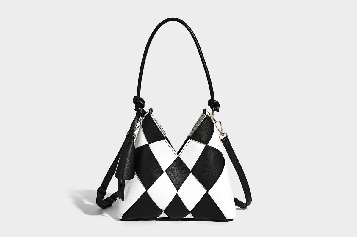Compact bucket shoulder bag with black-and-white diamond patchwork panels, knotted top handle, gold-tone hardware, and