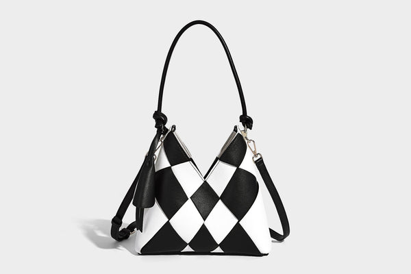 Compact bucket shoulder bag with black-and-white diamond patchwork panels, knotted top handle, gold-tone hardware, and