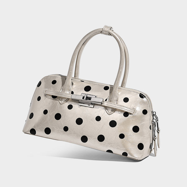 Glossy structured polka-dot satchel bag with dual top handles, silver turn-lock hardware, and detachable shoulder strap