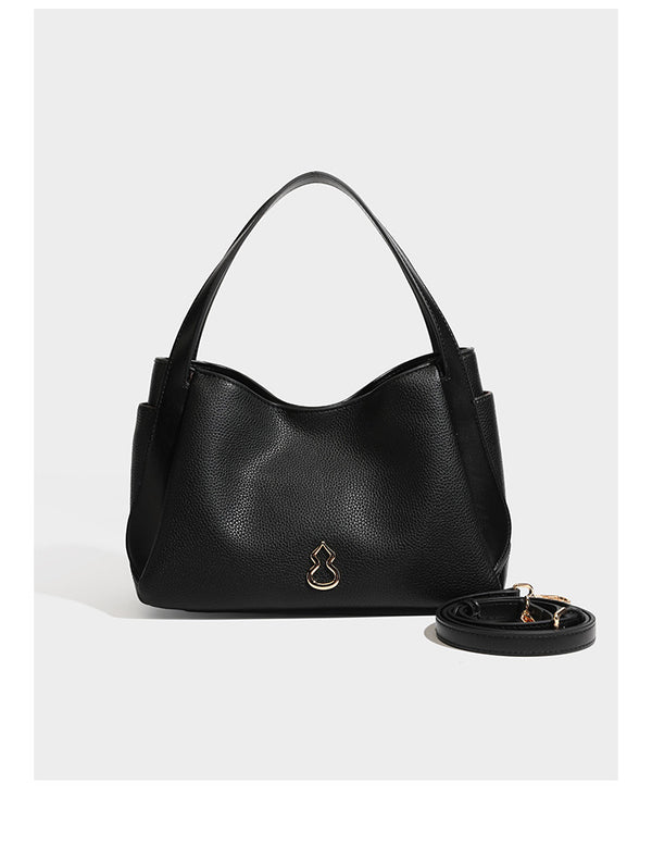 Schwarze Tote-Bag aus genarbtem Material in Lederoptik mit kürbisförmigen Beschlägen in Goldoptik, zwei Henkeln und abnehmbarem Umhängeriemen, Detailansicht