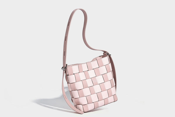 Hand-woven black-and-white checkerboard bucket bag with smooth black trim, silver-tone ring hardware, and adjustable