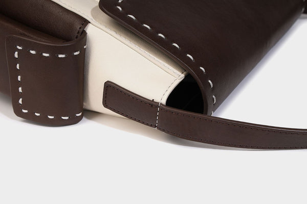 Structured flap crossbody bag in dark brown and cream color-block with white contrast stitching, adjustable shoulder strap
