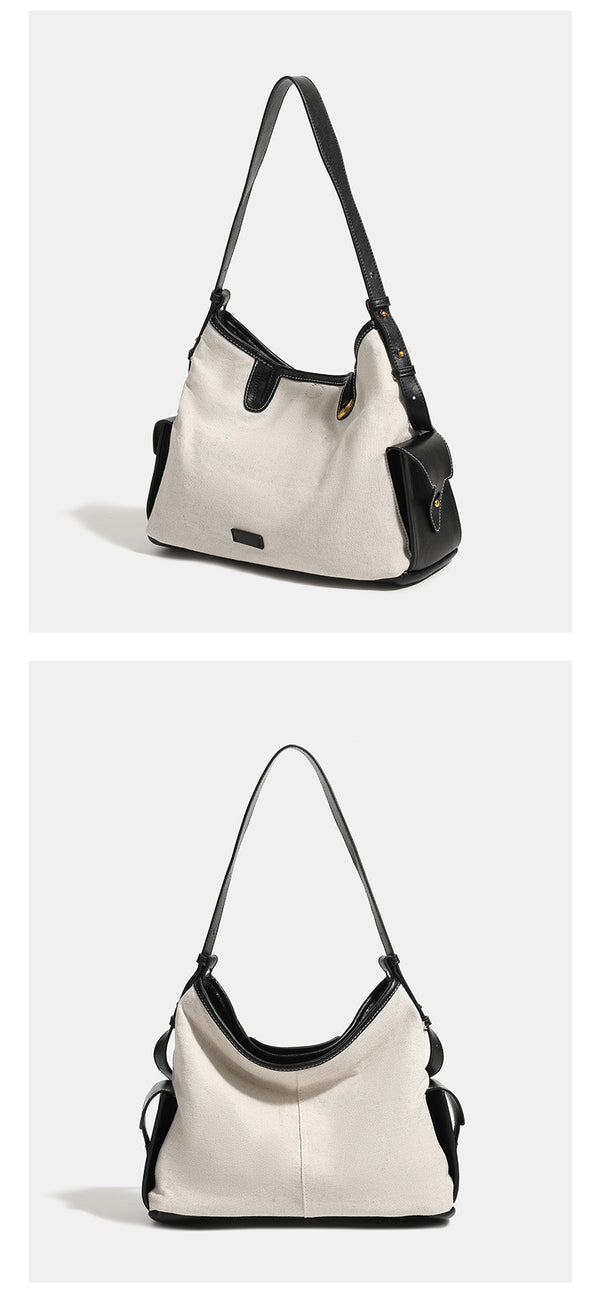 Off-white canvas shoulder bag with black leather-look trim, gold-tone ring hardware, top zip closure, side flap pocket, and