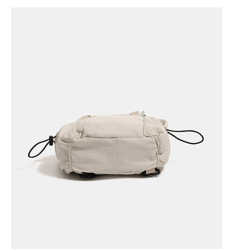 Small rounded mini backpack handbag in matte ripstop-texture fabric with top webbing handle, front pocket, side drawstring