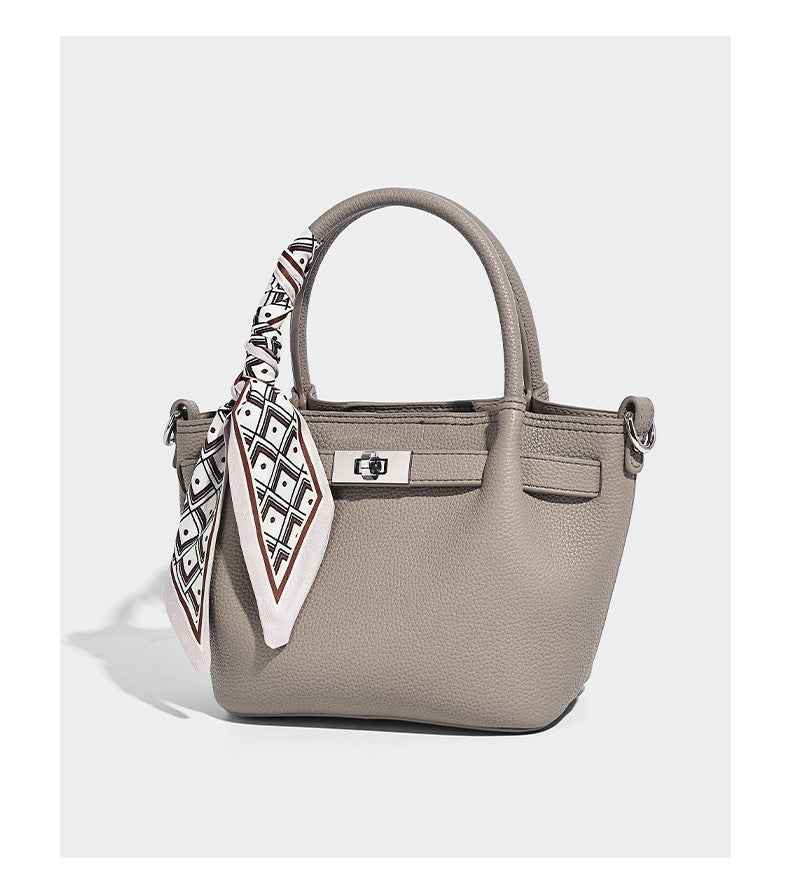 Kleine strukturierte Henkeltasche aus genarbtem Material in Taupe mit zwei Henkeln, bedrucktem Schalband, vorderem Drehverschluss und, Detail