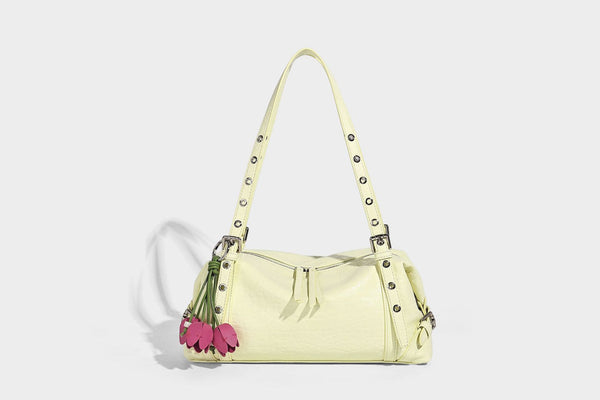 Pale yellow leather-look barrel bag with silver grommet-studded shoulder straps, top zip closure, and pink tulip floral